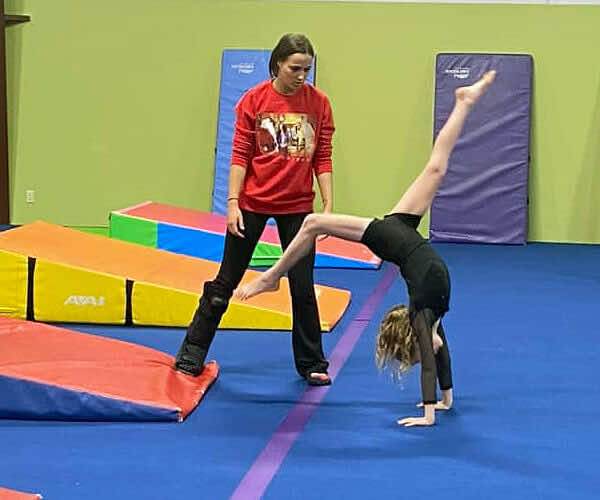 A recreational gymnast working on a cartwheel with her coach at Leah's Gymnastics & Cheerleading