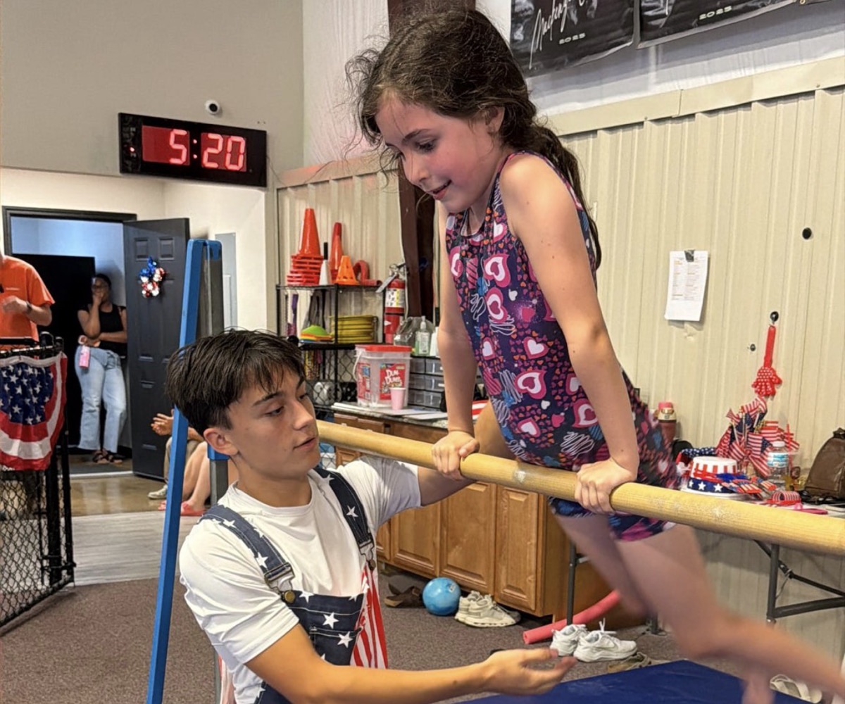 A coach spots a gymnast on the bar