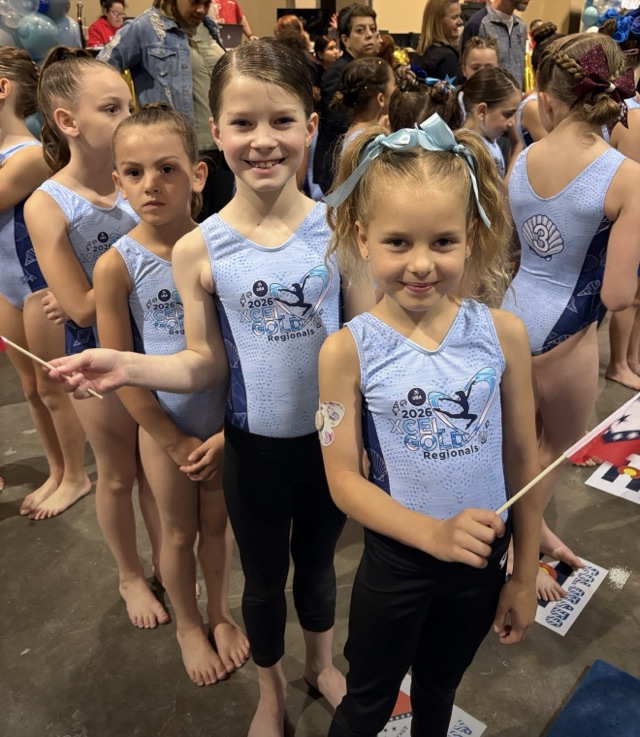 Two Xcel Gold Regionals gymnasts in light blue leotards